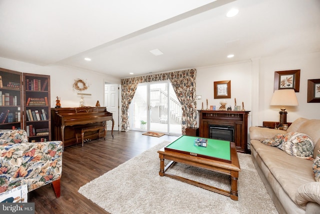 living area with recessed lighting, a glass covered fireplace, and wood finished floors
