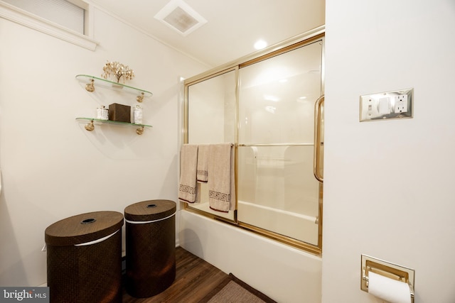 bathroom with combined bath / shower with glass door, wood finished floors, and visible vents
