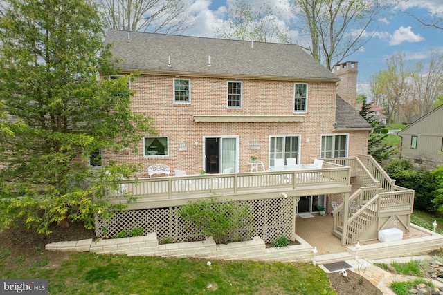 back of house featuring stairway, a chimney, brick siding, and a deck
