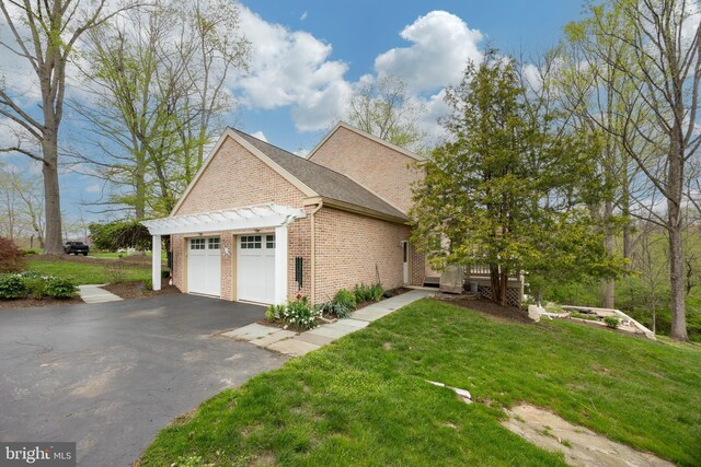 view of home's exterior with a lawn, brick siding, aphalt driveway, and a garage