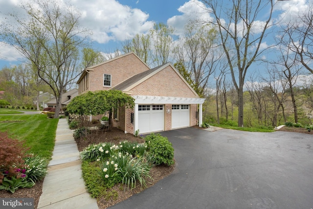 view of side of home featuring driveway, brick siding, and a garage