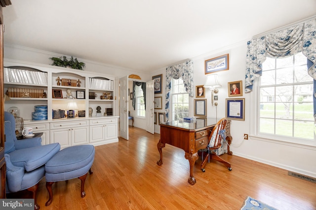 office space with light wood finished floors, baseboards, ornamental molding, and visible vents