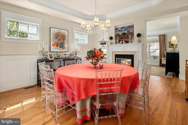 dining space featuring a raised ceiling, plenty of natural light, and ornamental molding