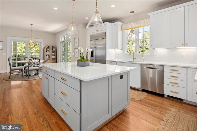 kitchen featuring recessed lighting, stainless steel appliances, light countertops, a sink, and a kitchen island