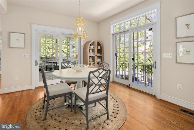 dining room featuring baseboards, light wood-style flooring, visible vents, and an inviting chandelier