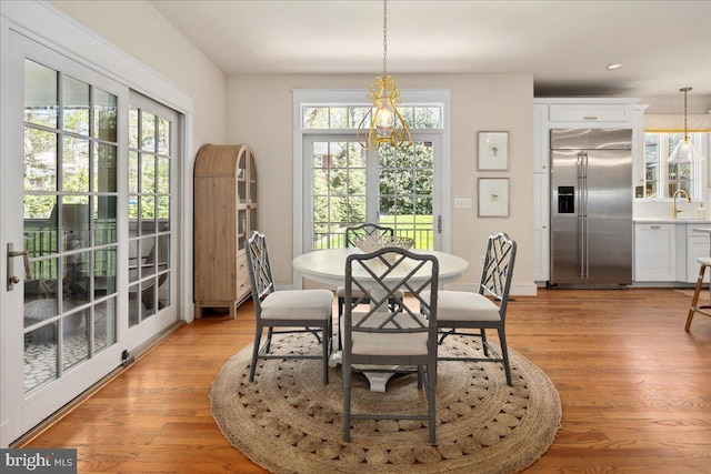 dining area with a notable chandelier, a healthy amount of sunlight, and light wood-style floors
