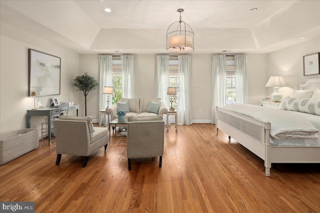 bedroom with baseboards, wood finished floors, a tray ceiling, and recessed lighting