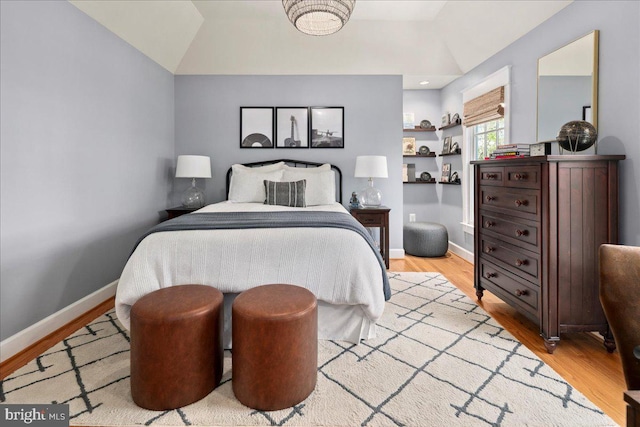 bedroom featuring baseboards, vaulted ceiling, and light wood finished floors