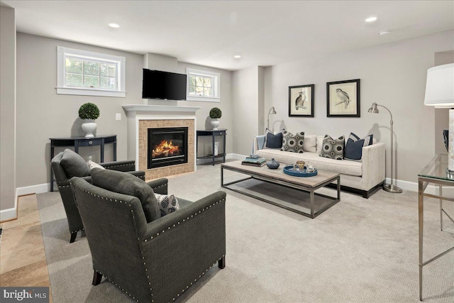 living area with recessed lighting, a tiled fireplace, baseboards, and light carpet