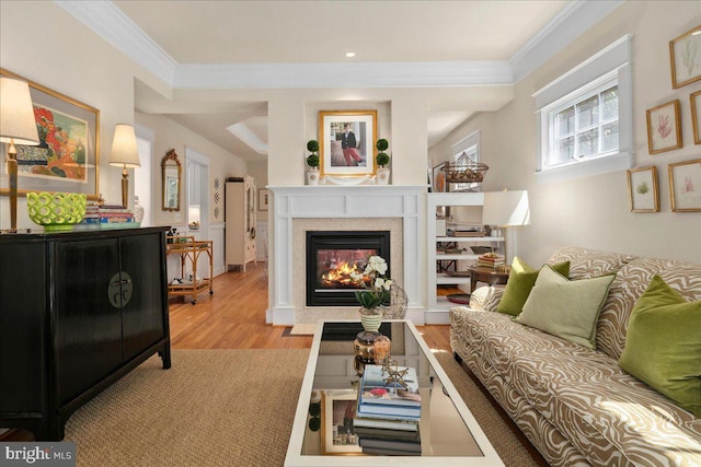 living room featuring recessed lighting, a glass covered fireplace, wood finished floors, and ornamental molding