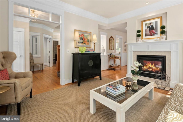 living area with a fireplace, light wood-style floors, and crown molding