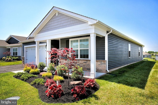 185 Petal Dr, Pottstown, PA 19464 - view of front of home with an attached garage, driveway, covered porch, stone siding, and a front yard
