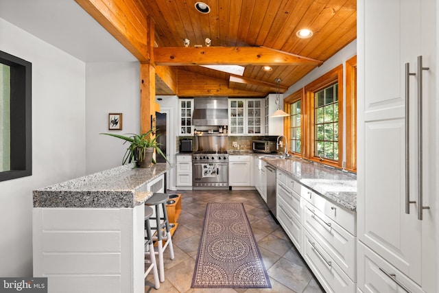 kitchen with appliances with stainless steel finishes, wall chimney exhaust hood, wooden ceiling, recessed lighting, and glass insert cabinets