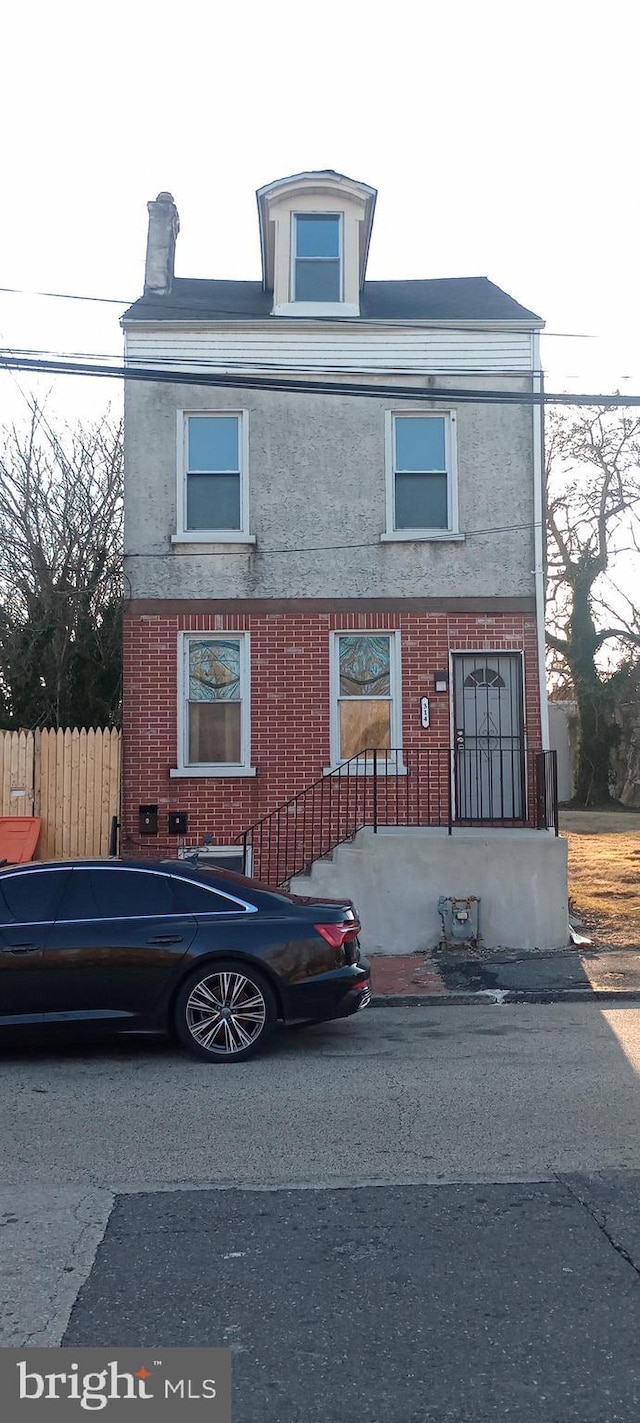view of front facade with fence and brick siding