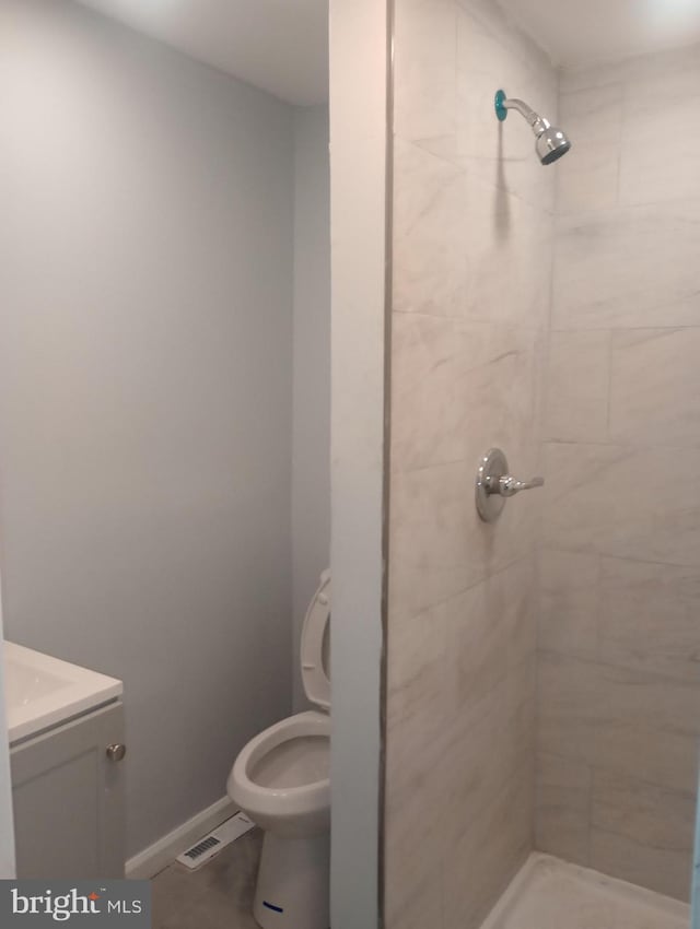 full bath with tiled shower, visible vents, and toilet