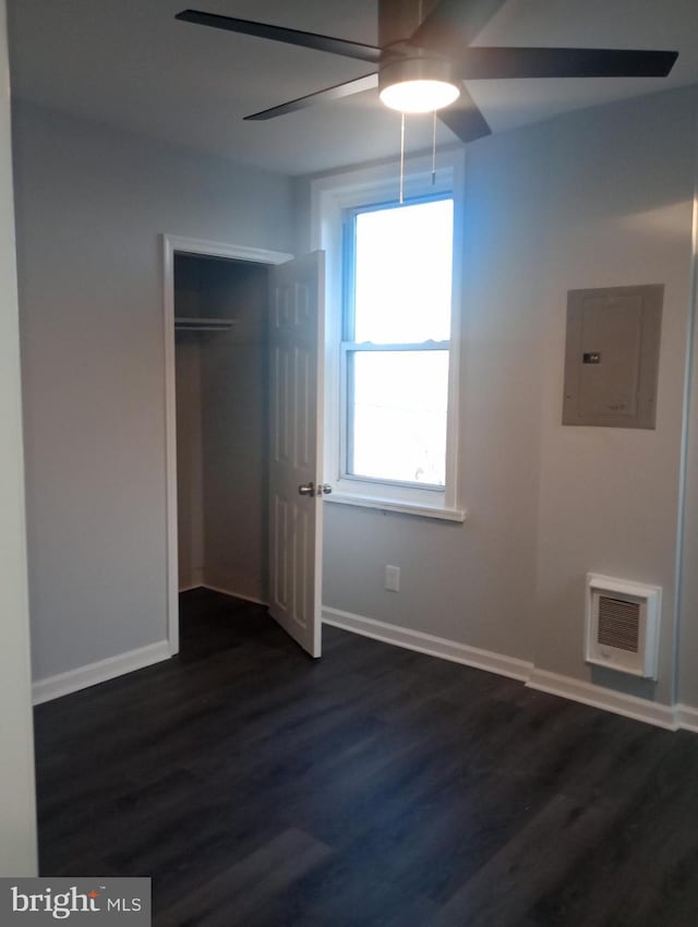 unfurnished bedroom featuring electric panel, dark wood-style flooring, baseboards, visible vents, and a closet
