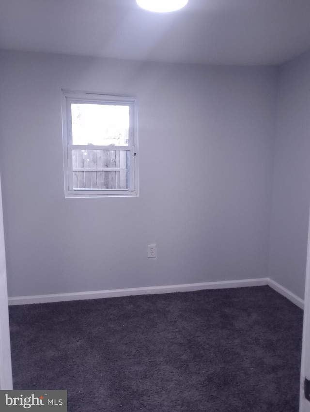 empty room with dark colored carpet and baseboards