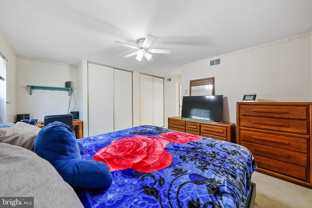 carpeted bedroom with multiple closets, visible vents, and a ceiling fan