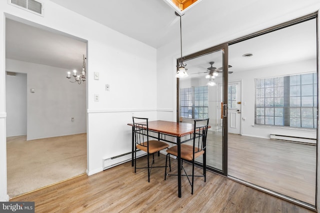 dining space with ceiling fan with notable chandelier, wood finished floors, visible vents, and a baseboard radiator