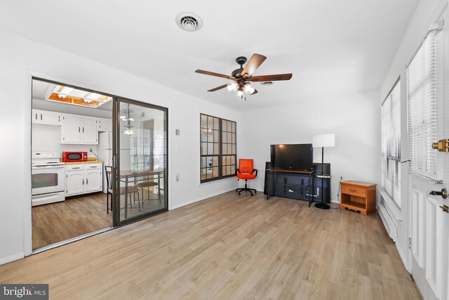 living room with light wood-style flooring, visible vents, ceiling fan, and a healthy amount of sunlight