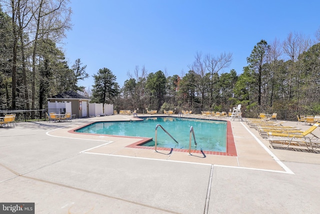 community pool with a patio area and fence