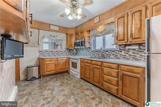 kitchen featuring a sink, light countertops, a ceiling fan, stainless steel microwave, and stone finish flooring