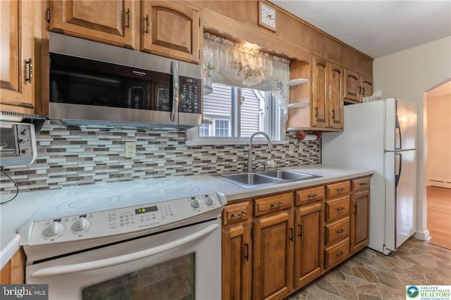kitchen featuring brown cabinetry, a sink, and white appliances
