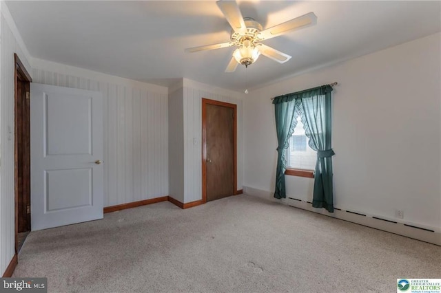 carpeted spare room featuring baseboards, a ceiling fan, and a baseboard heating unit