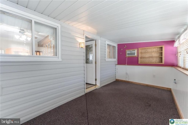 carpeted spare room with wooden ceiling, baseboards, and a wall mounted air conditioner