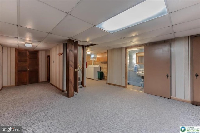 finished basement with carpet floors, a drop ceiling, and independent washer and dryer