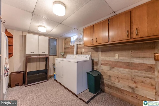 laundry room with wooden walls, light colored carpet, electric panel, washing machine and clothes dryer, and cabinet space
