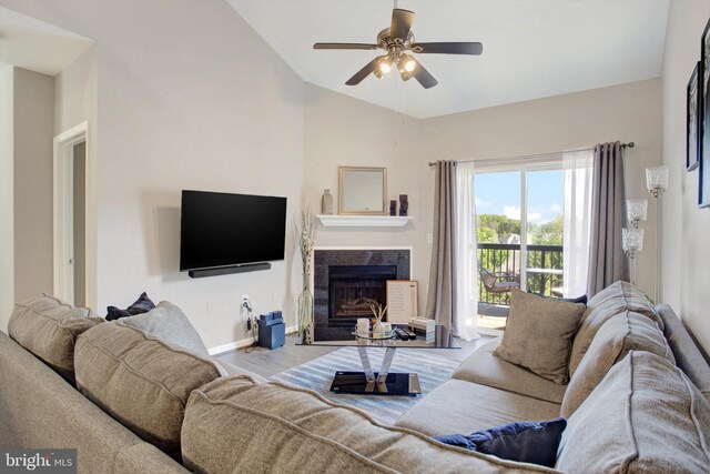 living area featuring wood finished floors, lofted ceiling, baseboards, ceiling fan, and a high end fireplace