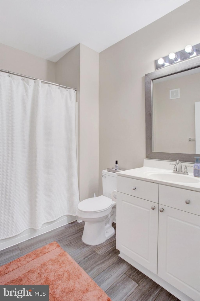 bathroom with vanity, toilet, wood finished floors, and shower / bath combination with curtain