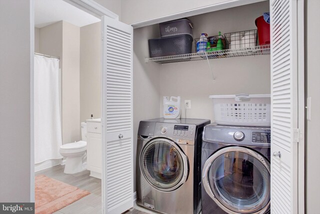 laundry room with laundry area, baseboards, independent washer and dryer, and wood finished floors