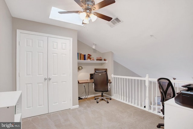 office area featuring a ceiling fan, light colored carpet, visible vents, and lofted ceiling with skylight
