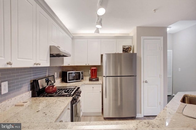 kitchen with white cabinets, stainless steel appliances, light wood-style flooring, and under cabinet range hood