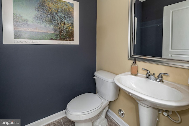half bathroom featuring a sink, baseboards, tile patterned floors, and toilet