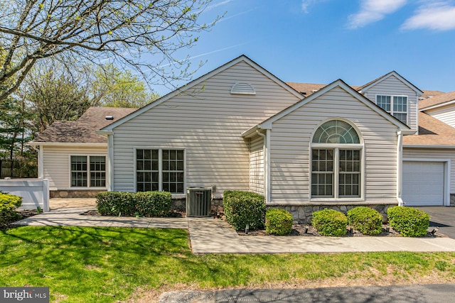 single story home with stone siding, central AC, an attached garage, and a front yard
