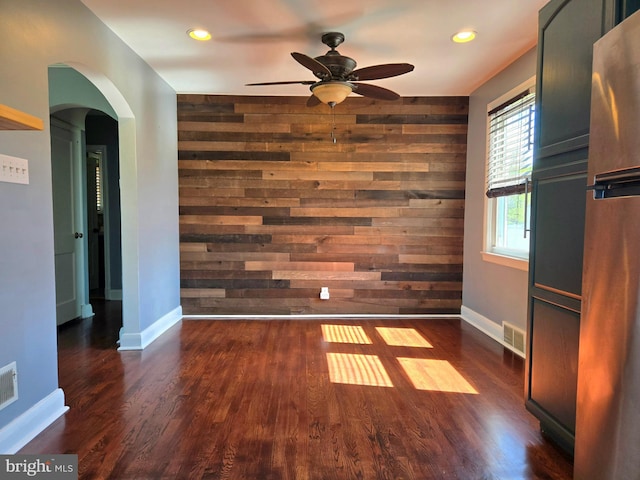 8464 Geneva Rd, Pasadena, MD 21122 - spare room featuring wood walls, a ceiling fan, arched walkways, baseboards, and dark wood-style flooring