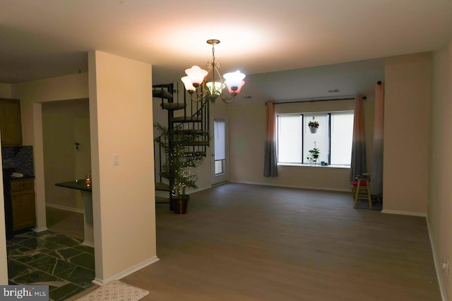 unfurnished dining area featuring wood finished floors, a chandelier, and baseboards