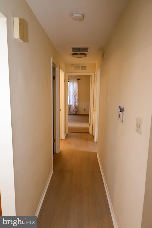 hall with light wood-type flooring and baseboards