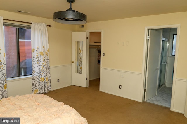bedroom with carpet floors, a walk in closet, ensuite bath, and a closet