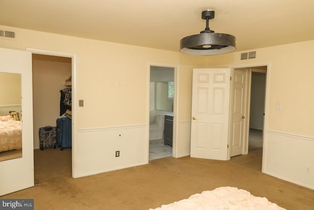 unfurnished bedroom featuring carpet floors, a walk in closet, a closet, and ensuite bath