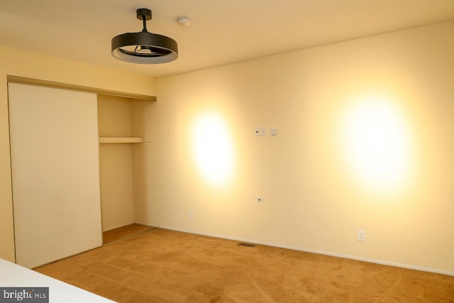 unfurnished bedroom with light carpet, a closet, and baseboards