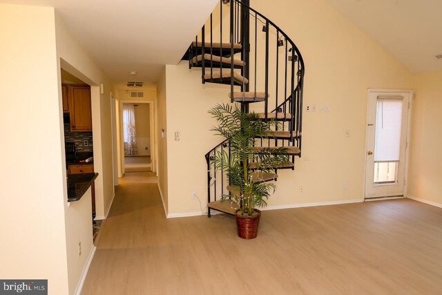 entrance foyer with wood finished floors, stairway, baseboards, and lofted ceiling