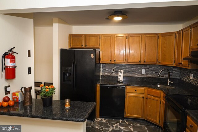 kitchen with black appliances, a sink, brown cabinets, under cabinet range hood, and backsplash