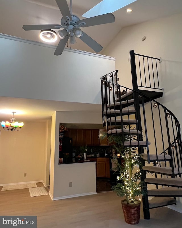 stairway featuring wood finished floors, a chandelier, ceiling fan, recessed lighting, and baseboards