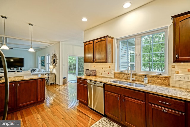 kitchen with hanging light fixtures, dishwasher, a sink, light stone counters, and open floor plan