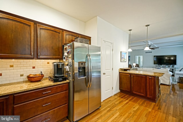 kitchen featuring stainless steel fridge, a peninsula, open floor plan, light wood-type flooring, and backsplash