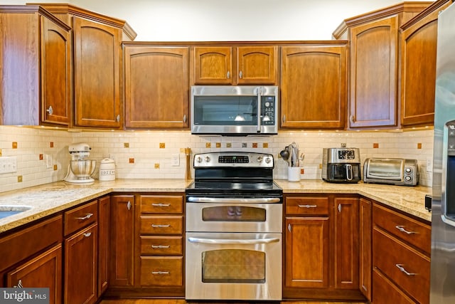 kitchen with light stone counters, backsplash, a toaster, and stainless steel appliances